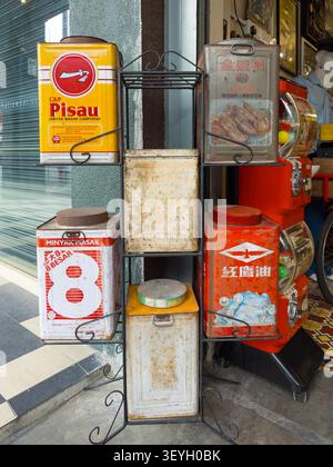 Vintage tin canisters including Cap Pisau cooking oil on a black metal shelf display outside a shop malaysia Stock Photo
