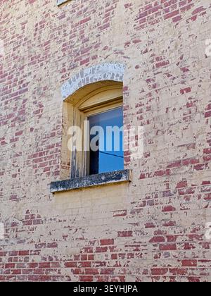 Window in arched window frame of old brick wall Stock Photo