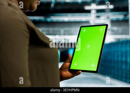 Data center administrator works with a chroma key tablet, using an editable screen to install and configure equipment. Stock Photo