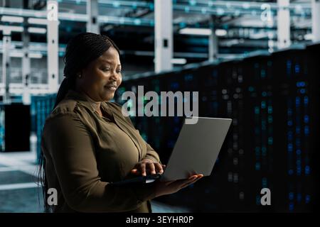 Cheerful systems engineer does maintenance on server facility electronics processing large datasets. Stock Photo