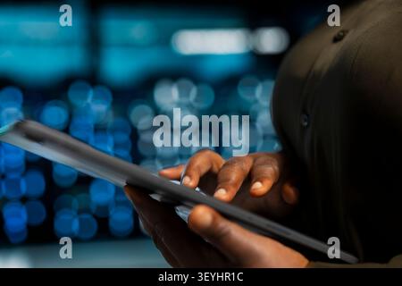 Data center programmer uses a tablet to install and configure equipment, supporting reliable infrastructure operations. Stock Photo