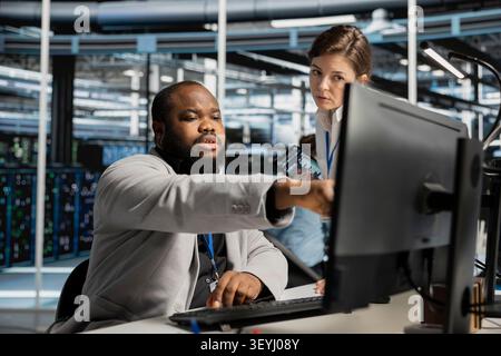 Data center manager uses a computer to run diagnostics, update servers and check infrastructure performance. Stock Photo