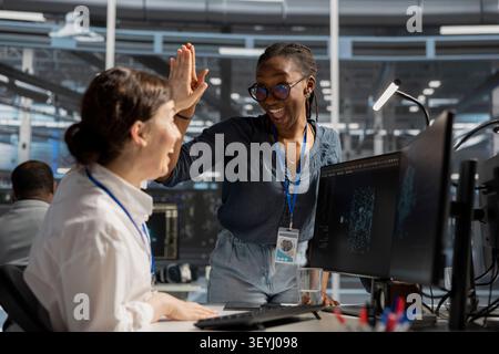 Delighted data center colleagues share a high five after improving system efficiency and completing AI implementation. Stock Photo