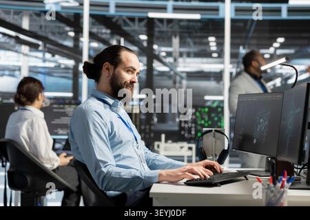 Smiling system administrator uses a computer to review server infrastructure, diagnostics and AI technology in a data center. Stock Photo