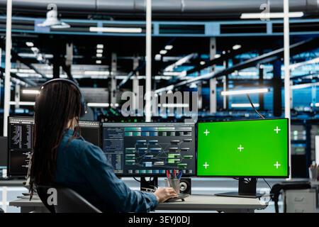 Data center programmer works with a chroma key computer, using an editable screen to review performance data. Stock Photo
