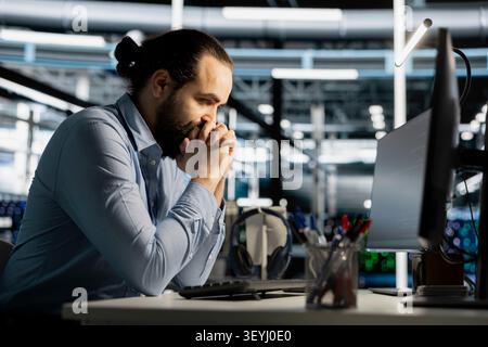 Data center engineer uses a computer to update server software, supporting reliable infrastructure operations. Stock Photo