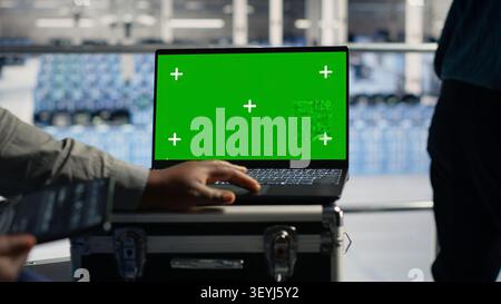 Data center technician works with a chroma key laptop, using an editable screen to monitor deep learning processes. Stock Photo