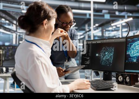 Smiling data center team works with digital devices while reviewing systems, scripts and server infrastructure. Stock Photo