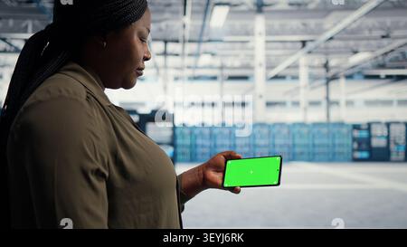 Data center administrator works with a chroma key smartphone, using an editable screen to watch a technical tutorial. Stock Photo