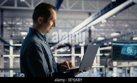 Data center engineer uses a laptop to manage AI training datasets and database workflows inside a server room. Stock Photo