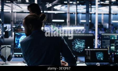 Engineering team checks infrastructure diagnostics on a computer workstation in a server room for IT maintenance. Stock Photo