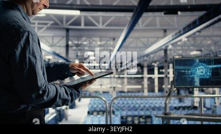 Server room employee reviews tablet data charts to track system health. Stock Photo