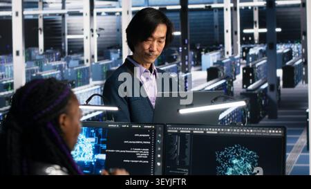 IT colleagues collaborate in a data center while reviewing AI diagnostics and infrastructure performance. Stock Photo