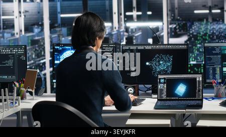 System administrator monitors data center metrics on a digital device to improve equipment performance. Stock Photo