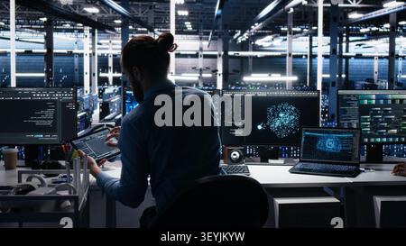 Administrator programs on a laptop in a data center with generative AI assistance. Stock Photo