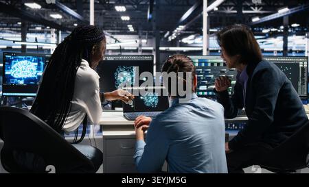 Server room computer scientists working with AI to check digital infrastructure diagnostics with IT specialists collaborating in server facility. Stock Photo