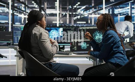 Server facility engineering team rolling out AI solutions optimizing equipment. Server facility teamworking colleagues working together, applying AI to minimize systems downtime. Stock Photo