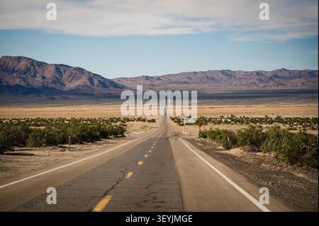 A long straight highway running through the desert near the Nevada California border. Stock Photo