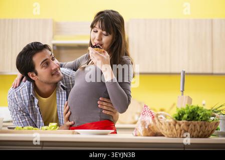 Man and pregnant woman preparing salad in kitchen Stock Photo