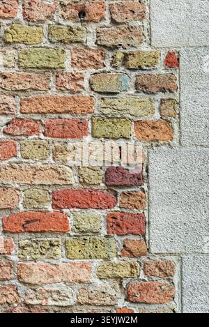Full-frame old mixed brick and stone wall with a pale plaster edge, showing layered masonry texture and historic surface detail. Stock Photo