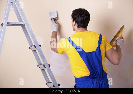 Young contractor employee applying plaster on wall Stock Photo