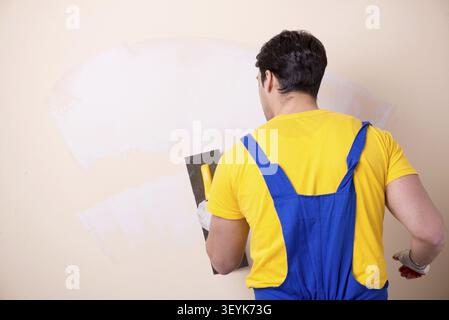 Young contractor employee applying plaster on wall Stock Photo