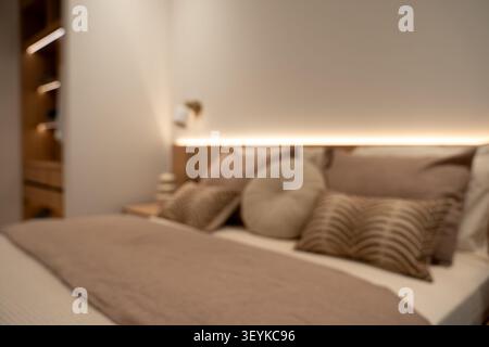 Blurred view of modern bedroom interior with decorative pillows. Stock Photo