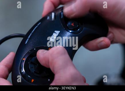 Close-up of hands holding a Sega Mega Drive game controller during a retro gaming event. Stock Photo