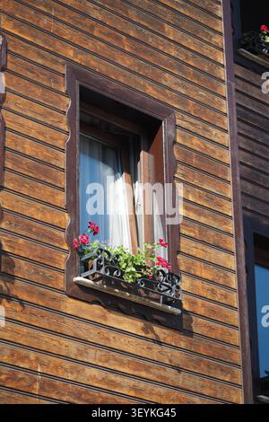 Wooden building with flowers in windows on a sunny day Stock Photo