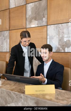 Caucasian male female colleagues working together at reception desk Stock Photo