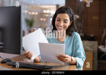 Hotel receptionist reviewing documents at front desk Stock Photo