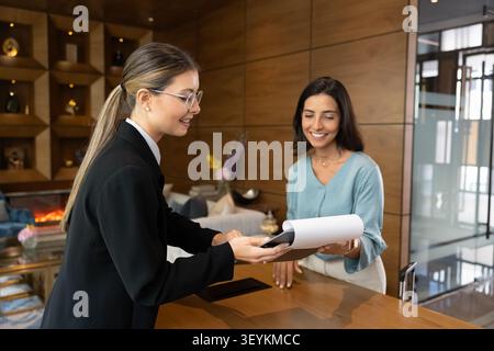 Hotel guest reviewing registration form, confirming booking details at reception Stock Photo