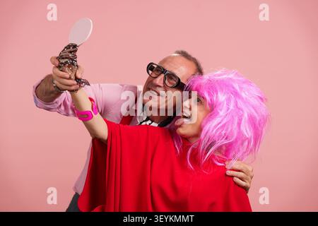 Mature couple taking playful selfie with pink wig Stock Photo