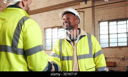 Engineer, men and shaking hands in workshop for welcome, renovation collaboration or deal. Construction, smile or handshake with people for greeting Stock Photo