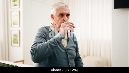 Drinking water, health and senior man in home for wellness, nutrition or diet benefits in bedroom. Retirement, thirsty person and glass with liquid Stock Photo