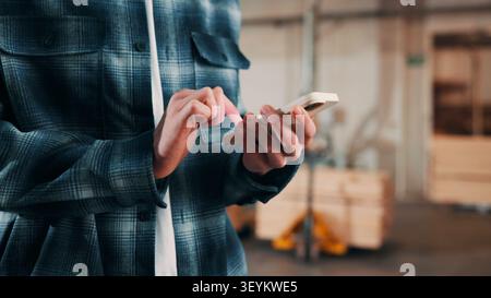 Man, hands and carpenter typing with phone in workshop for online network or shipping order. Male person, carpentry or texting on mobile smartphone Stock Photo