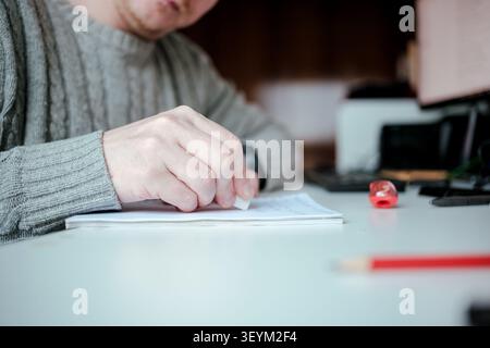 Hand erasing drawing or writing mistake on white paper on a desk Stock Photo