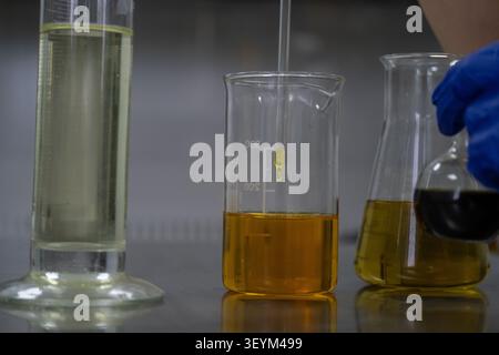 Close up of a glass pipette dispensing a liquid sample into a laboratory beaker during routine analytical testing. The image illustrates sample prepar Stock Photo