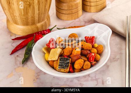 Closeup of colorful snack mix featuring roasted nuts seaweed squares red green peppers in white ceramic bowl Stock Photo