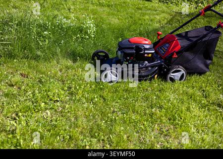 Red Motorized Lawnmower in Action on Lawn Stock Photo