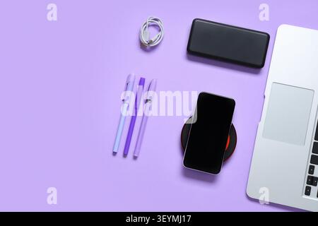 Composition with modern gadgets and pens on lilac background Stock Photo