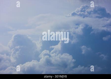 Fluffy White Cumulus Clouds Against a Deep Blue Sky. A wide-angle view of bright, billowing white clouds scattered across a vibrant blue summer sky. Stock Photo