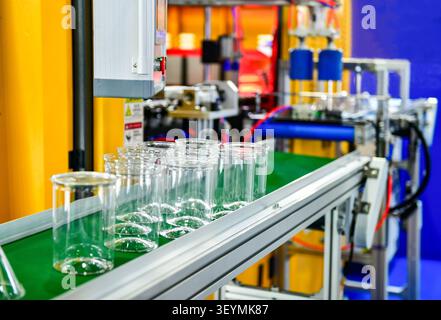 Automated manufacturing process of disposable clear plastic cups on conveyor belt in factory Stock Photo