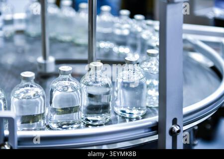 Biotechnology factory conveyor line transporting clear vaccine liquid glass containers Stock Photo