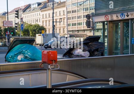 This red emergency stop button at a Vienna subway escalator entrance is designed to halt movement if needed. Beside it, discarded trash bags await pic Stock Photo