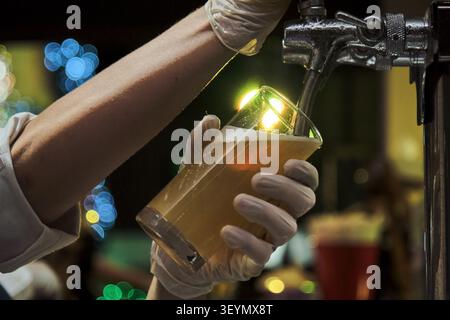 a man pouring beer into a tall clear beer mug in party Stock Photo