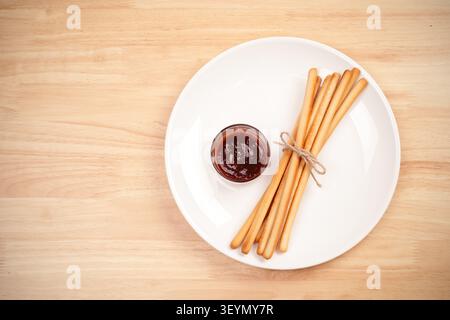 pack of breadsticks with ketchup dipping sauce in white dish on wood table Stock Photo
