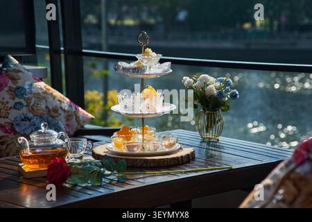 a tower of desserts served with a jar of tea on the table waiting for customers in riverside restaurant Stock Photo