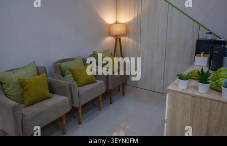 A room with three cushioned seats and a lamp with other amenities. Stock Photo