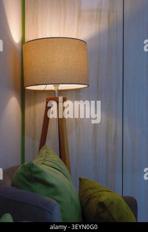 A room with three cushioned seats and a lamp with other amenities. Stock Photo